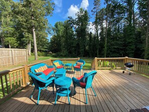 Une terrasse en bois avec des meubles en osier et un barbecue.