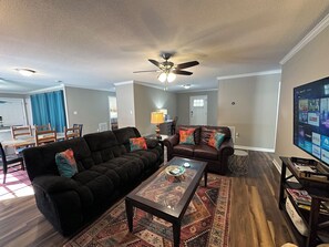Ein Wohnzimmer mit einem dunkelbraunen Sofa, einem Couchtisch und einem Fernseher, der einen Startbildschirm zeigt.