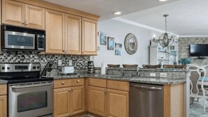 Una cocina con armarios de madera, horno de acero inoxidable, microondas y lavavajillas.
