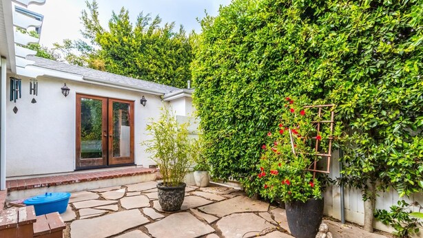 A stone patio with potted plants and a small table.
