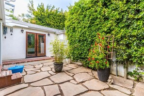 A stone patio with potted plants and a small table.