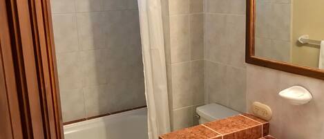 Une salle de bain avec un lavabo en marbre, des toilettes, une douche avec un rideau et un miroir.