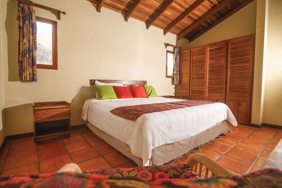 A bedroom with a wooden bed, a nightstand, a chair, and a wardrobe.