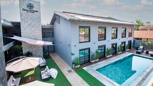 A modern building with a swimming pool, outdoor seating, and a sign reading "Flores do Carno". - Pousada Flores do Carmo (Pirenópolis)