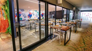A modern restaurant with glass doors, white chairs, and tables. - Pousada Flores do Carmo (Pirenópolis)