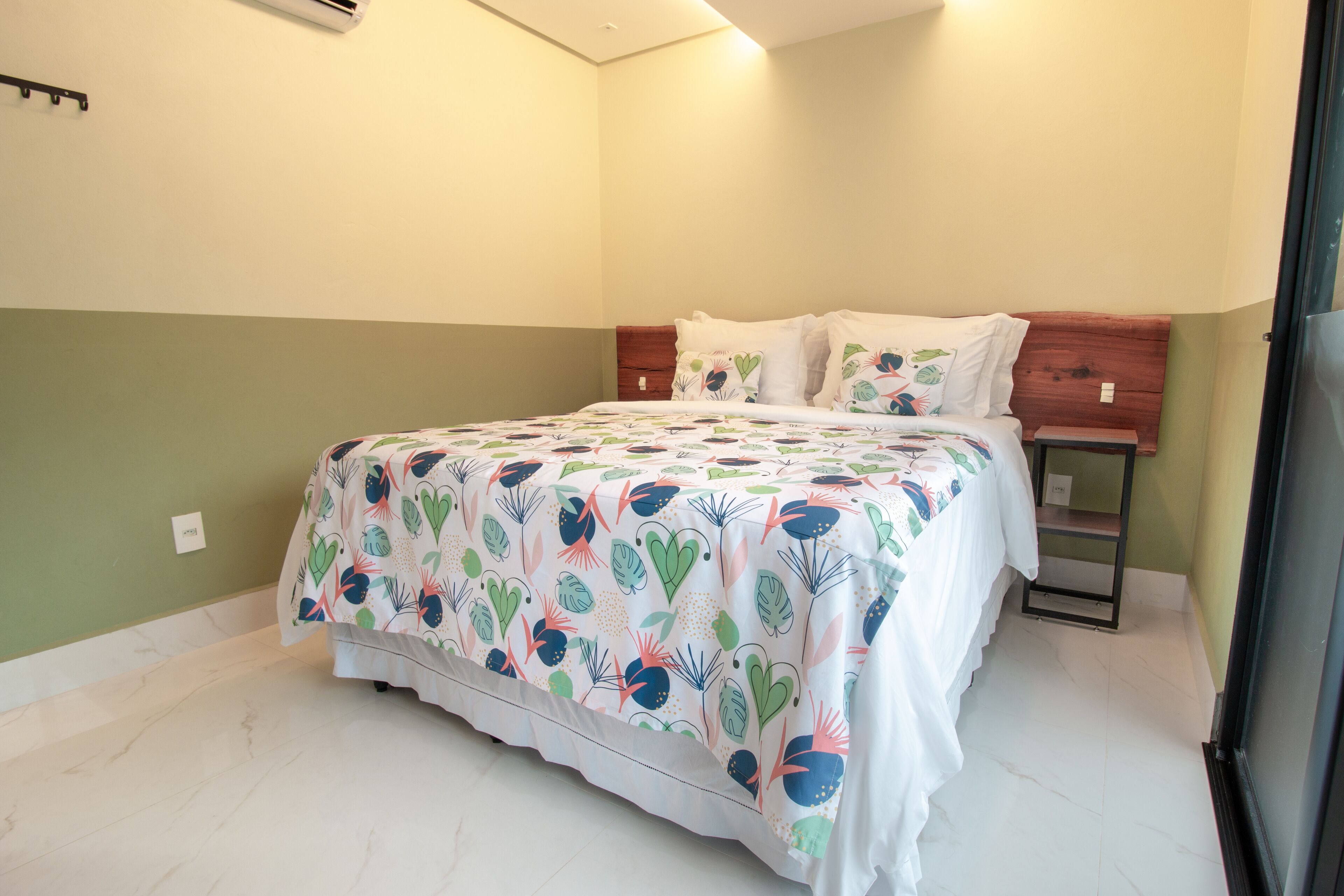 Un dormitorio con cama, mesita de noche y estante en la pared.