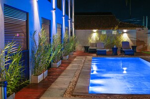 Una piscina al aire libre, sombrillas, sillones reclinables de piscina