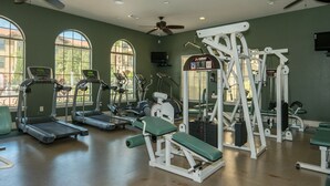 Un gimnasio con cintas de correr, elípticas y equipo de levantamiento de pesas.