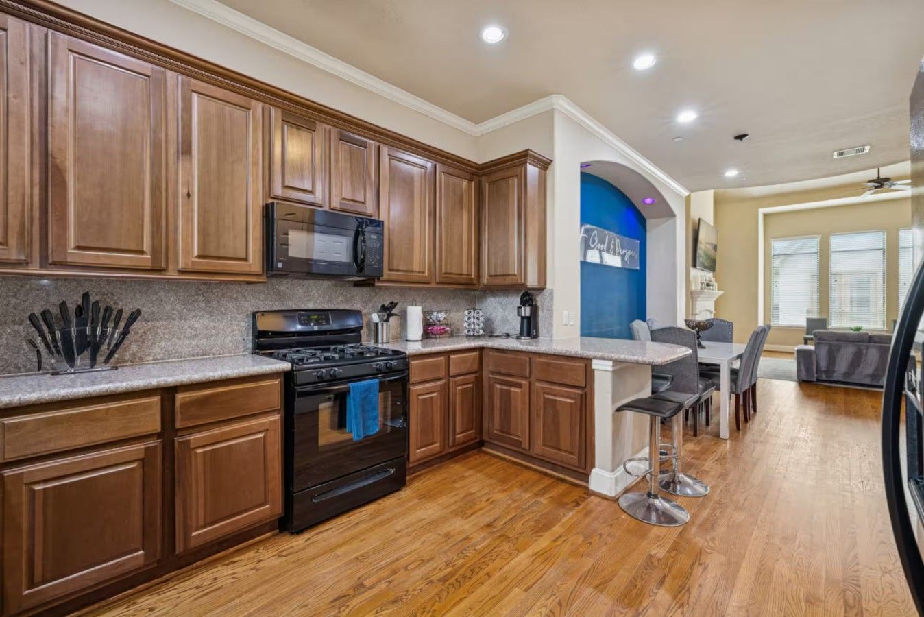 Una cocina con armarios de madera, estufa de acero inoxidable y microondas.