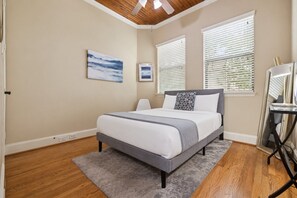 Un dormitorio con cama, escritorio y dos ventanas con persianas.