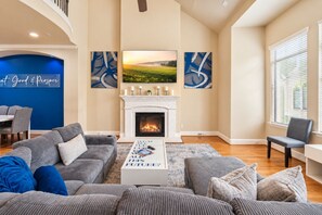 A living room with a fireplace, a dining area, and artwork on the walls.