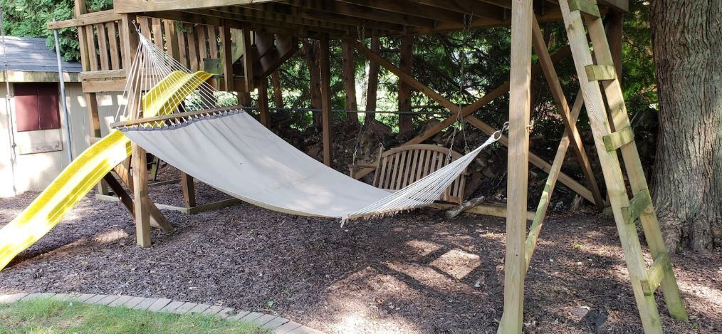 A hammock under a wooden structure with a slide.
