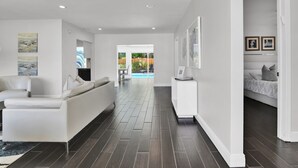 A spacious living area with a sofa, a dining table, and a view of a pool. - Villa Coastal Cove Sparkling Pool Close to Beach BBQ En-Suite (Boca Raton)
