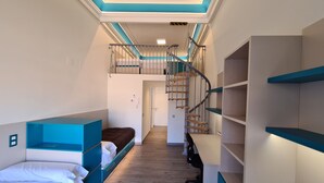 A room with bunk beds, a desk, and a spiral staircase.