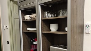 A kitchen with a built-in microwave, toaster, and shelves with dishes and glasses.