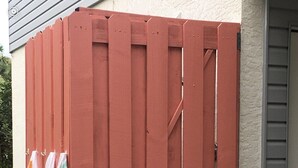 Une clôture en bois rouge sur laquelle sont suspendues des serviettes.