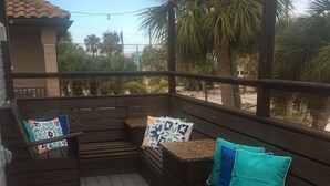 Une terrasse en bois dotée de sièges intégrés et d’une rambarde, qui offre une vue sur un espace paysager agrémenté de palmiers.