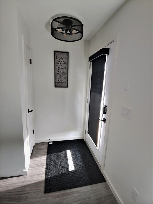Un couloir avec un tapis noir, un ventilateur de plafond et une citation inspirante sur le mur.