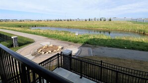 A riverside walkway with a paved path, a small pond, and a grassy area with trees in the background. - Serene 2 bedroom condo with balcony and lakeview plus Free Parking (Winnipeg)