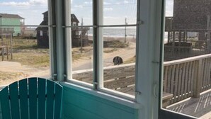Quarto com vista para a praia, um deck de madeira na área externa e uma cadeira azul-turquesa no interior.