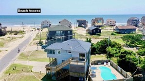 Zona residencial com acesso à praia, com casas que incluem piscina e deck de madeira.