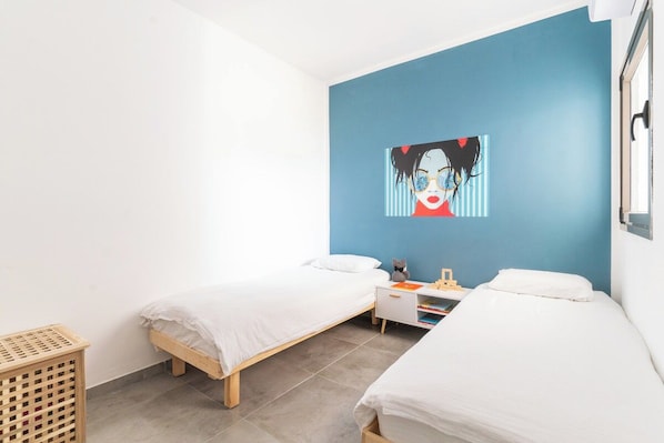 A room with two single beds, a small desk, and a wall-mounted artwork.