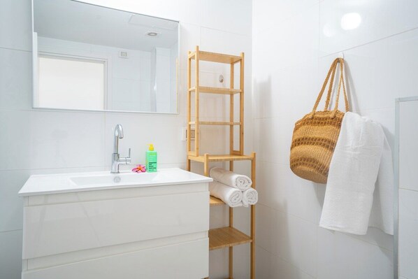 A bathroom with a white sink, mirror, and wooden towel rack.