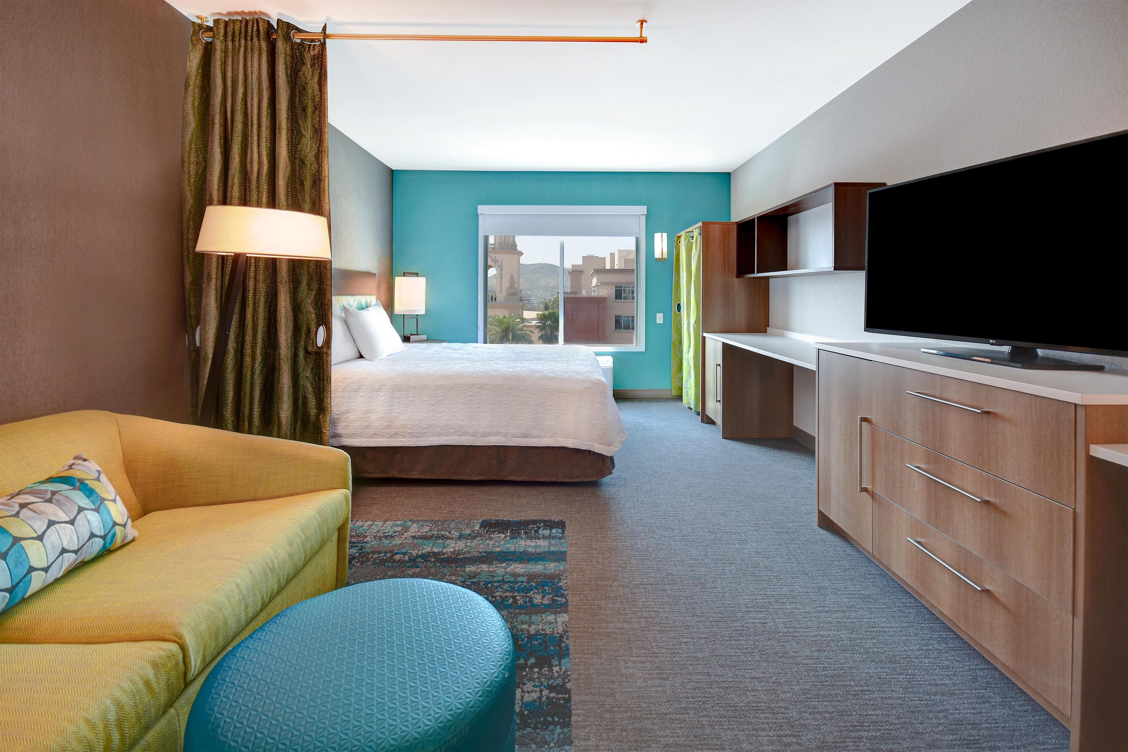 A hotel room with a bed, a sofa, a television, and a desk.