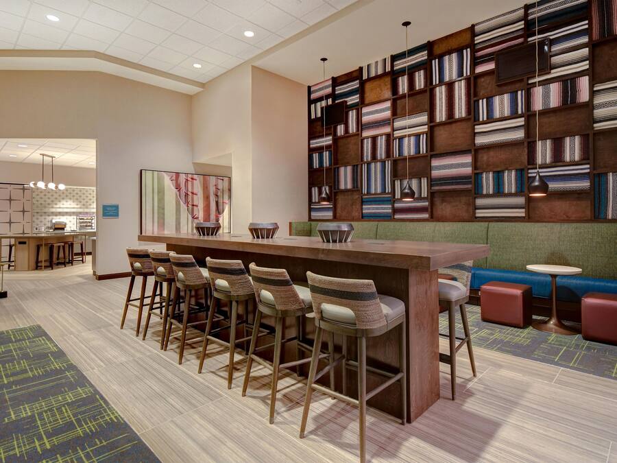 A bar area with stools, a counter, and a wall of patterned textiles.