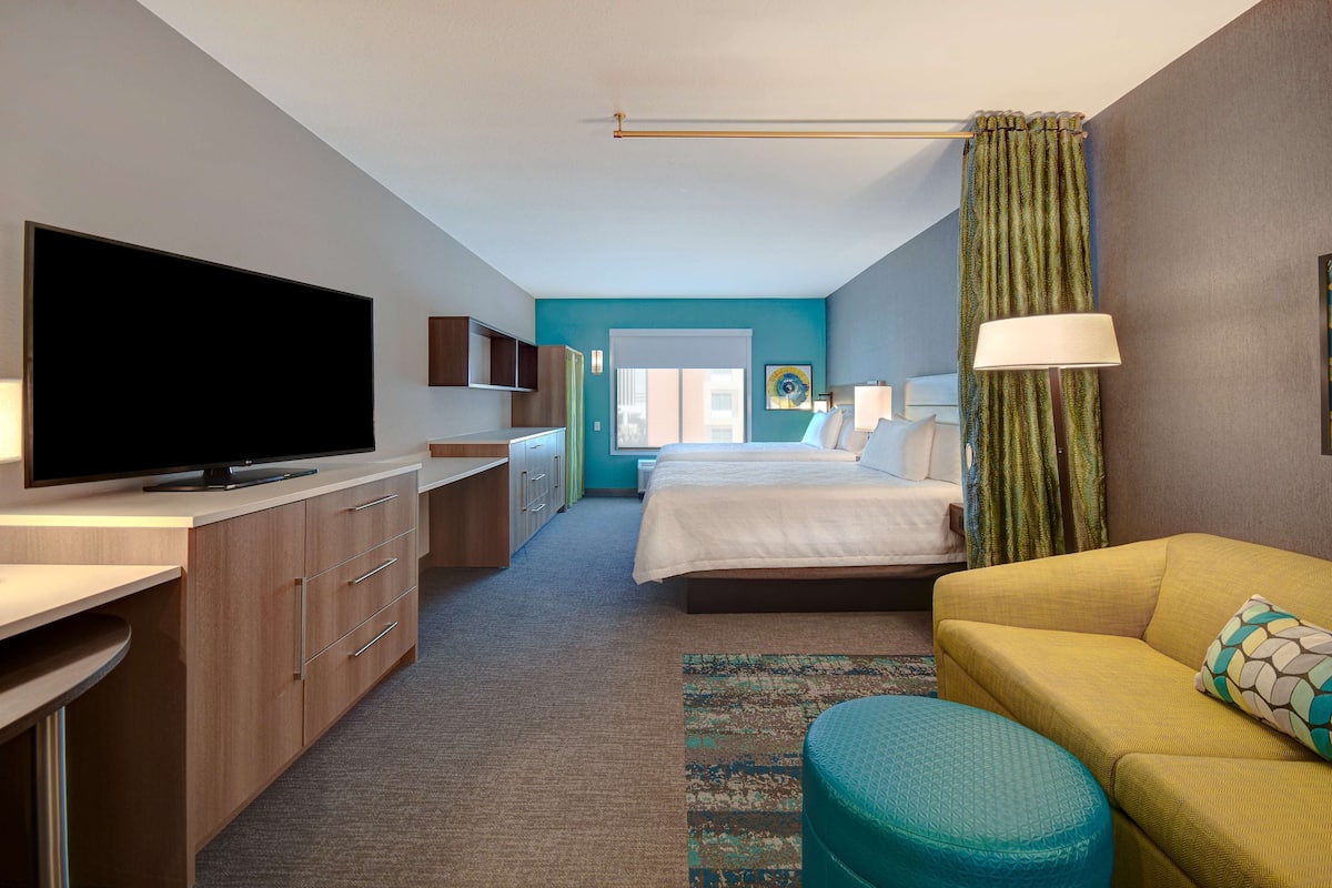 A hotel room with a TV, a bed, a sofa, and a desk.