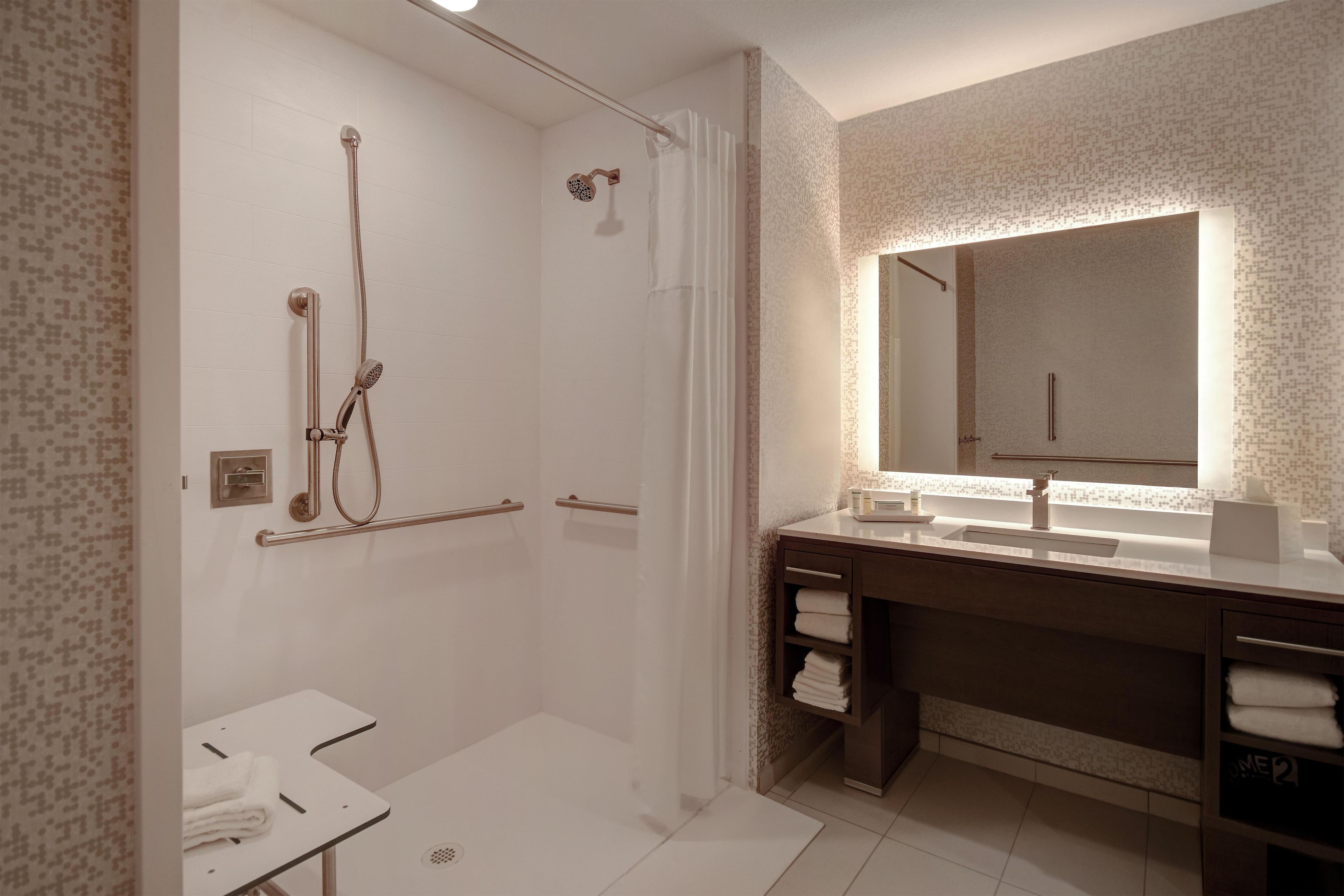 Une salle de bain moderne avec une douche à l’italienne, un meuble-lavabo doté d’un grand miroir et des toilettes.