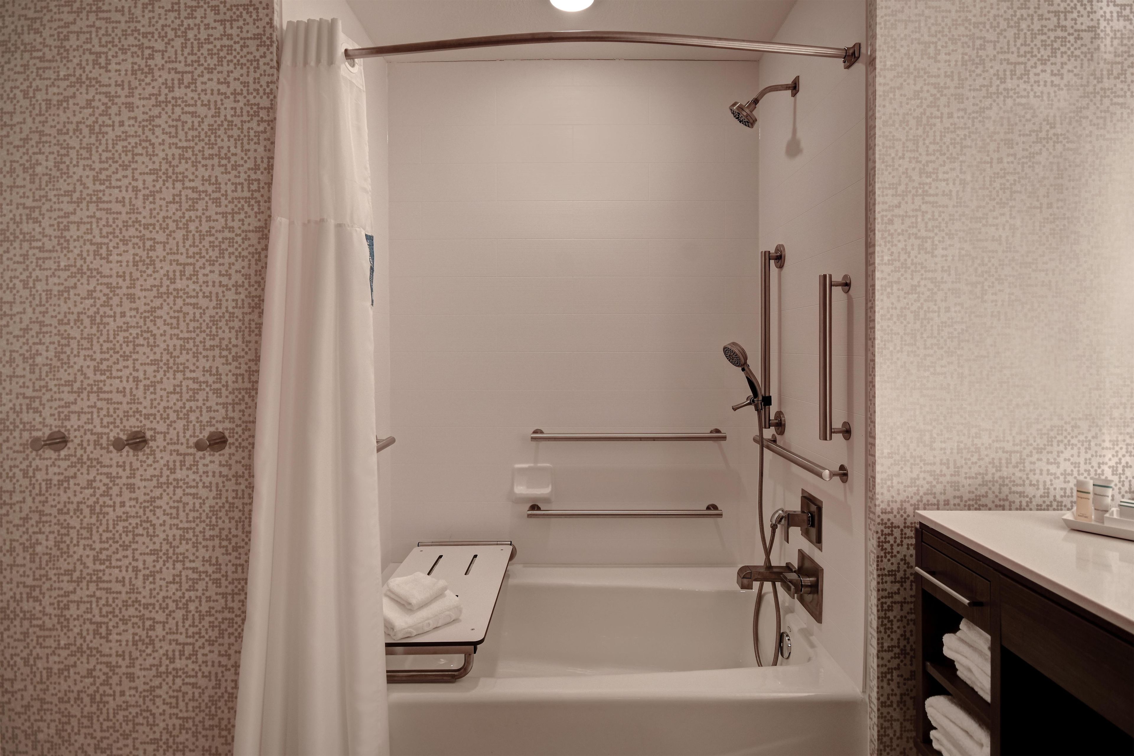 Un baño moderno con ducha a nivel, barras de apoyo y un perchero.