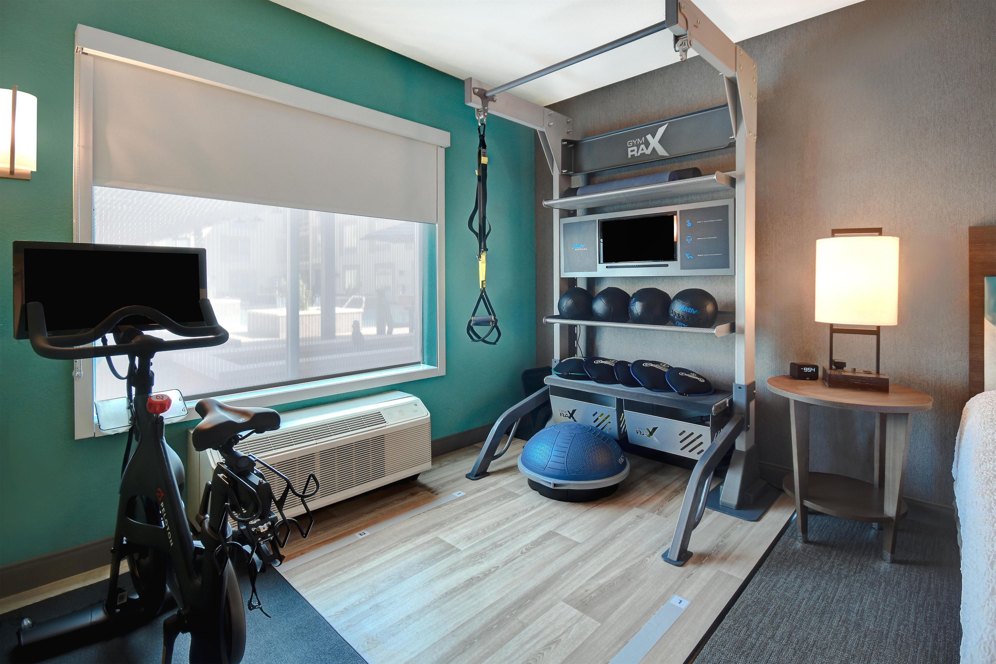 A gym with exercise equipment, a treadmill, and a wall-mounted TV.