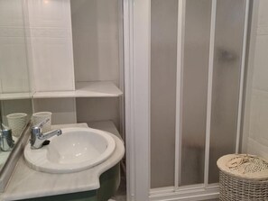 Un bagno con lavandino bianco, specchio e box doccia.