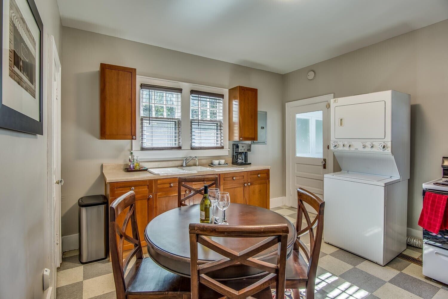 Una cocina compacta con armarios de madera, un refrigerador blanco, una estufa y una mesa de comedor con sillas.