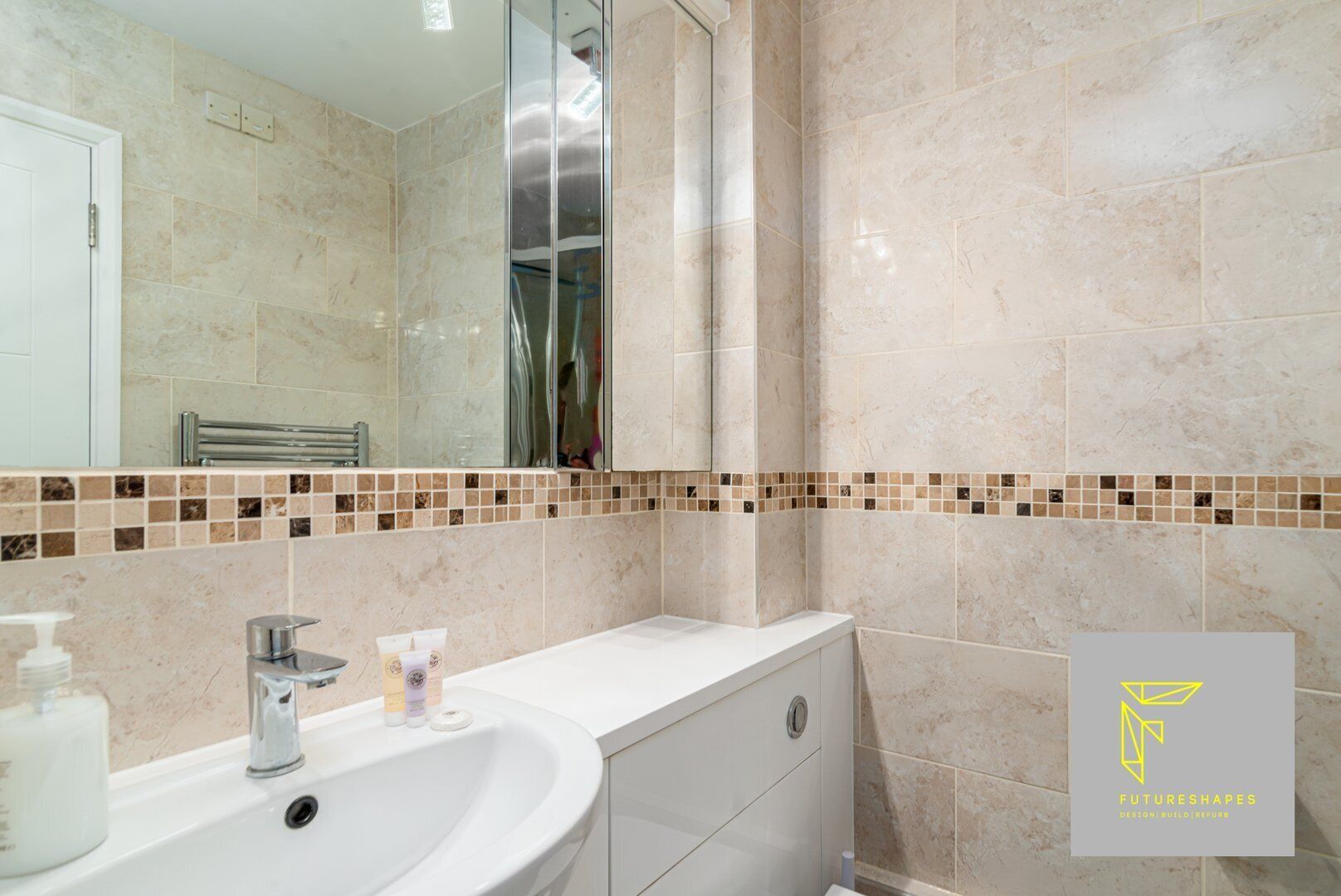 A bathroom with a white sink, mirror, and tiled walls.