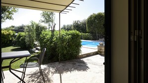 An outdoor patio with a table and chairs, a pool, and a garden with various plants and trees. - Karrua House cottage with pool in Modica (Modica)