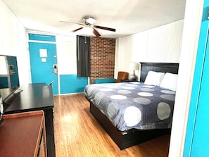 A hotel room with a bed, a desk, a chair, a ceiling fan, and a brick wall. - Rodeway Inn Nashville (Nashville)