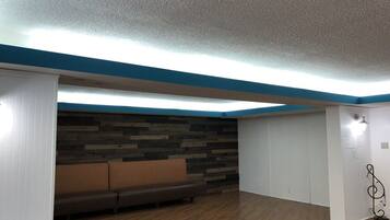 Una habitación con piso de madera, un sofá marrón, pared blanca con detalles azules y techo con textura.