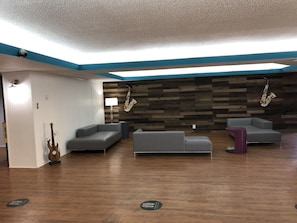 A modern lounge area with a wooden wall, grey sofas, and a guitar. - Rodeway Inn Nashville (Nashville)
