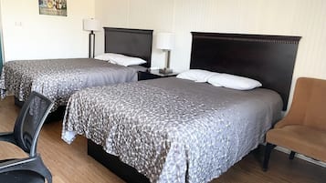 Habitación de hotel con dos camas, una silla, un escritorio y una lámpara.