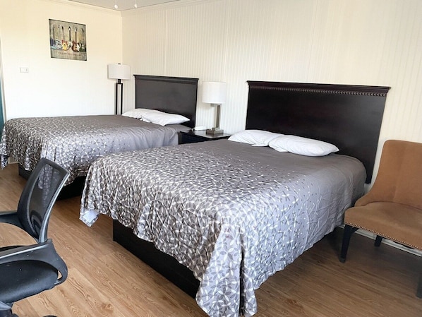 A hotel room with two beds, a chair, a desk, and a lamp. - Rodeway Inn Nashville (Nashville)