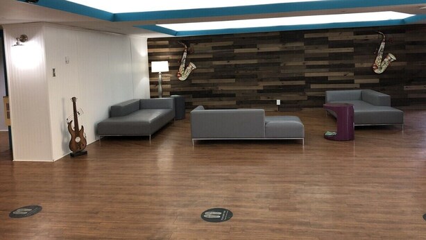 A modern lounge area with a wooden wall, grey sofas, and a guitar. - Rodeway Inn Nashville (Nashville)