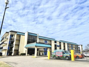 A multi-story building with a blue roof, a parking area, and a van with a sign. - Rodeway Inn Nashville (Nashville)