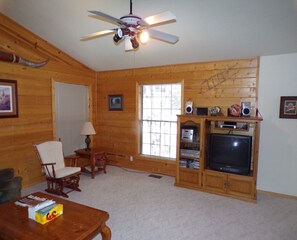 Relax in this inviting living room with a high ceiling fan, TV, and comfortable seating area.