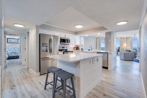 Una cocina moderna con una isla central, electrodomésticos de acero inoxidable y vista al área de estar.