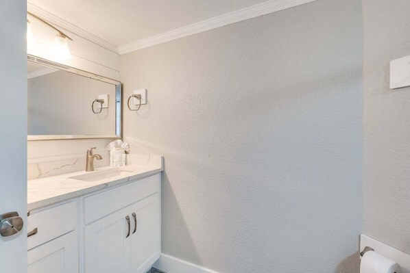 A bathroom with a white vanity, a large mirror, and a towel rack.