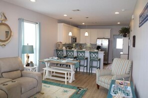 Cozy living space with a dining area, sofa, and kitchenette featuring a refrigerator, microwave, and island with bar stools.