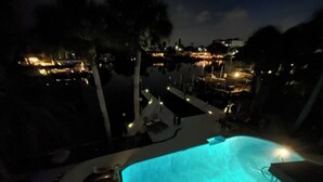 A nighttime view of a swimming pool with surrounding lounge chairs and a deck area. - Excellent home for multiple families.  Enjoy the pool or fish off the dock. (Clearwater)