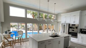 A spacious kitchen with a large island, white cabinetry, and a view of a swimming pool. - Excellent home for multiple families.  Enjoy the pool or fish off the dock. (Clearwater)